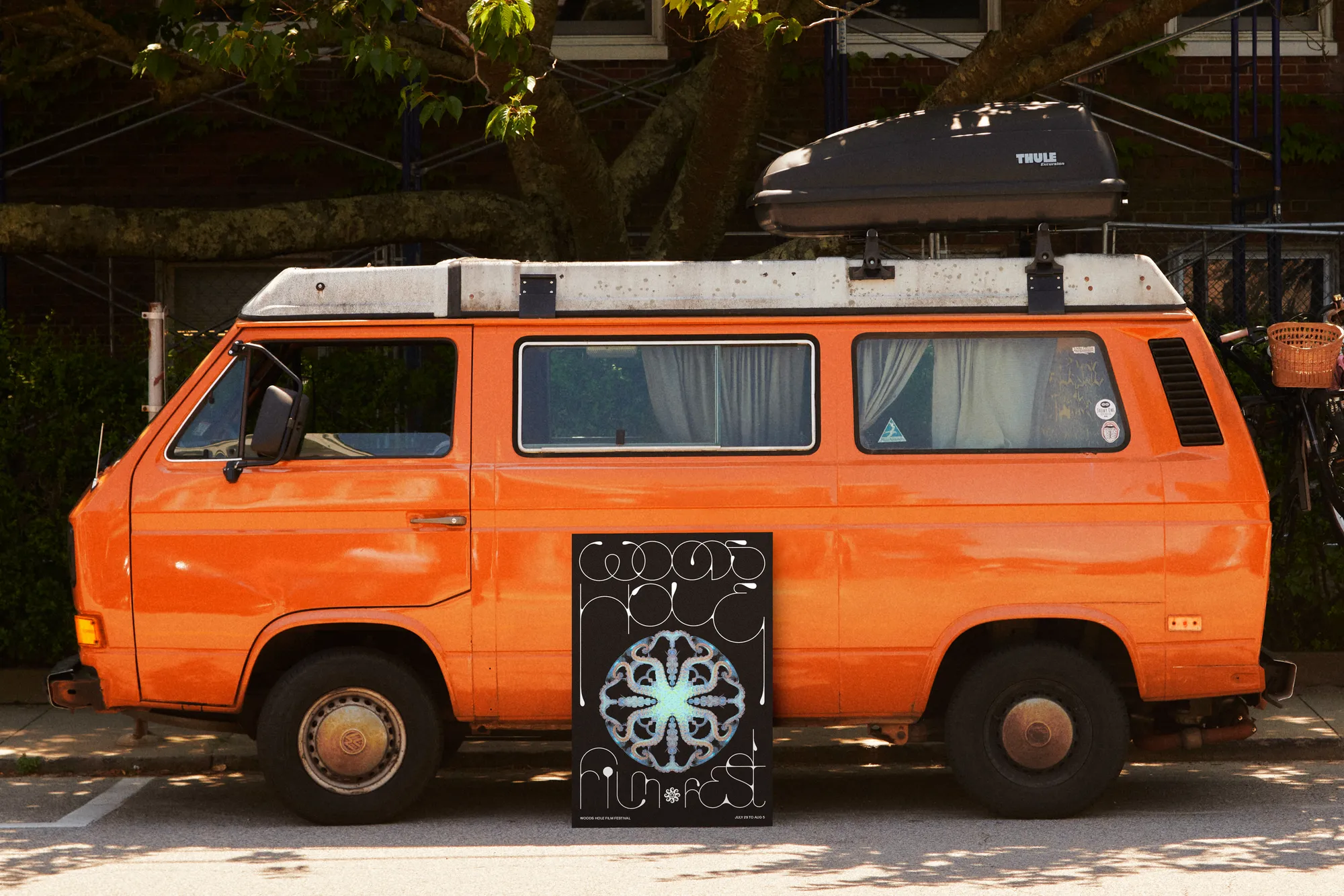An orange camper van with the festival’s kaleidoscopic octopus poster propped against it