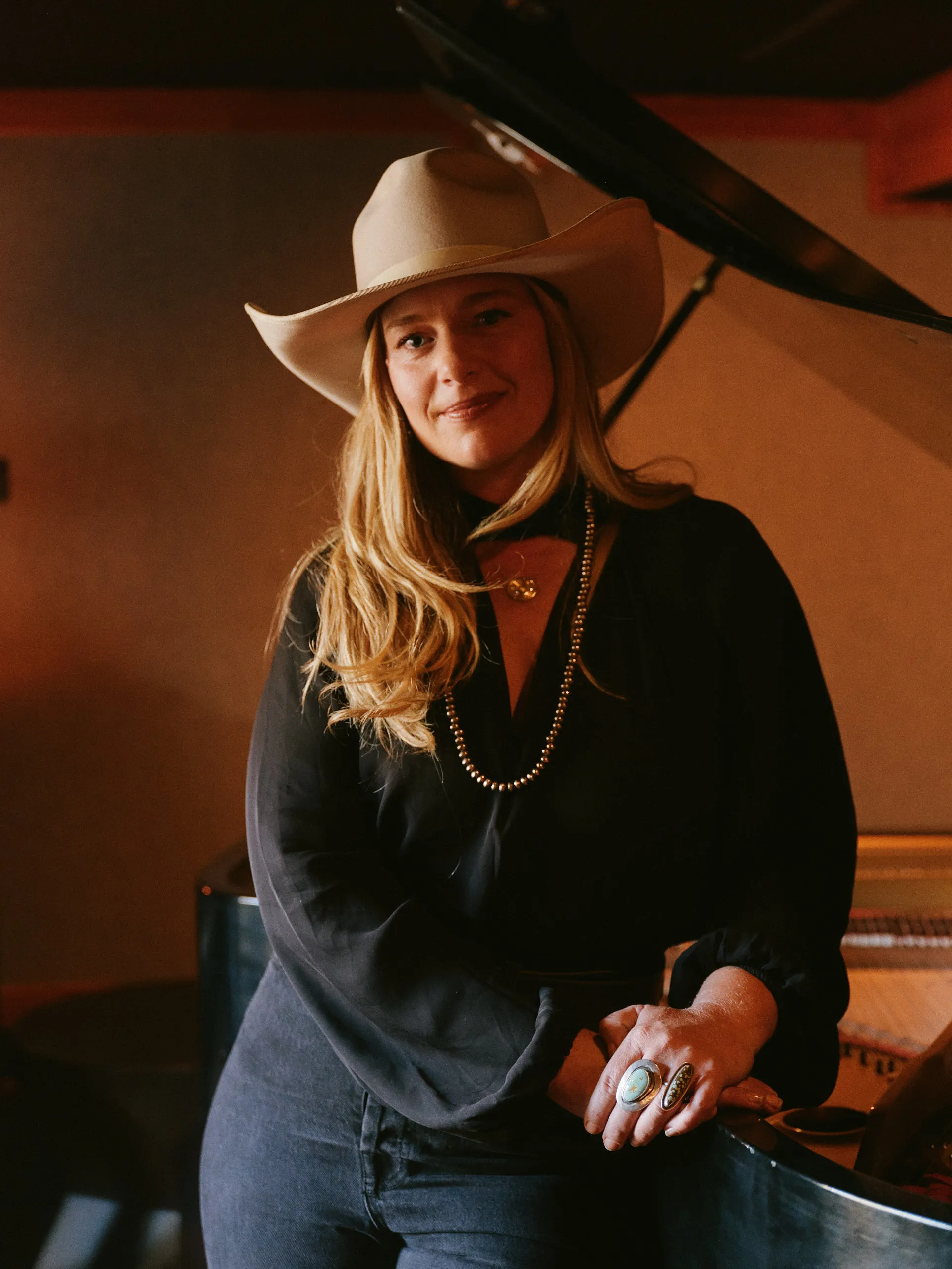 A guest in a cream cowboy hat beside a grand piano at Americana First